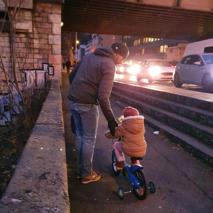 Un père avec son enfant en trottinette sur le quai des Etroits
